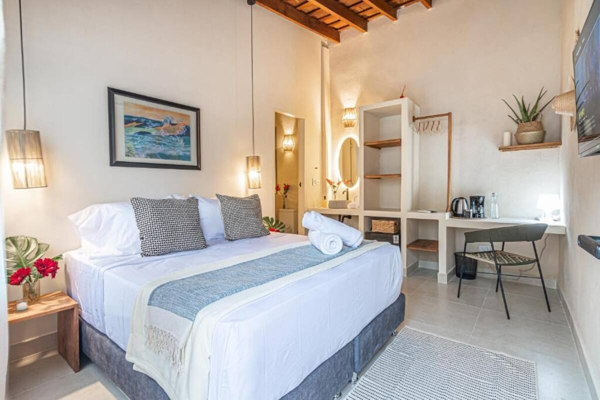 Ein Schlafzimmer mit Bett, Nachttisch, Lampe und Schreibtisch mit Stuhl.