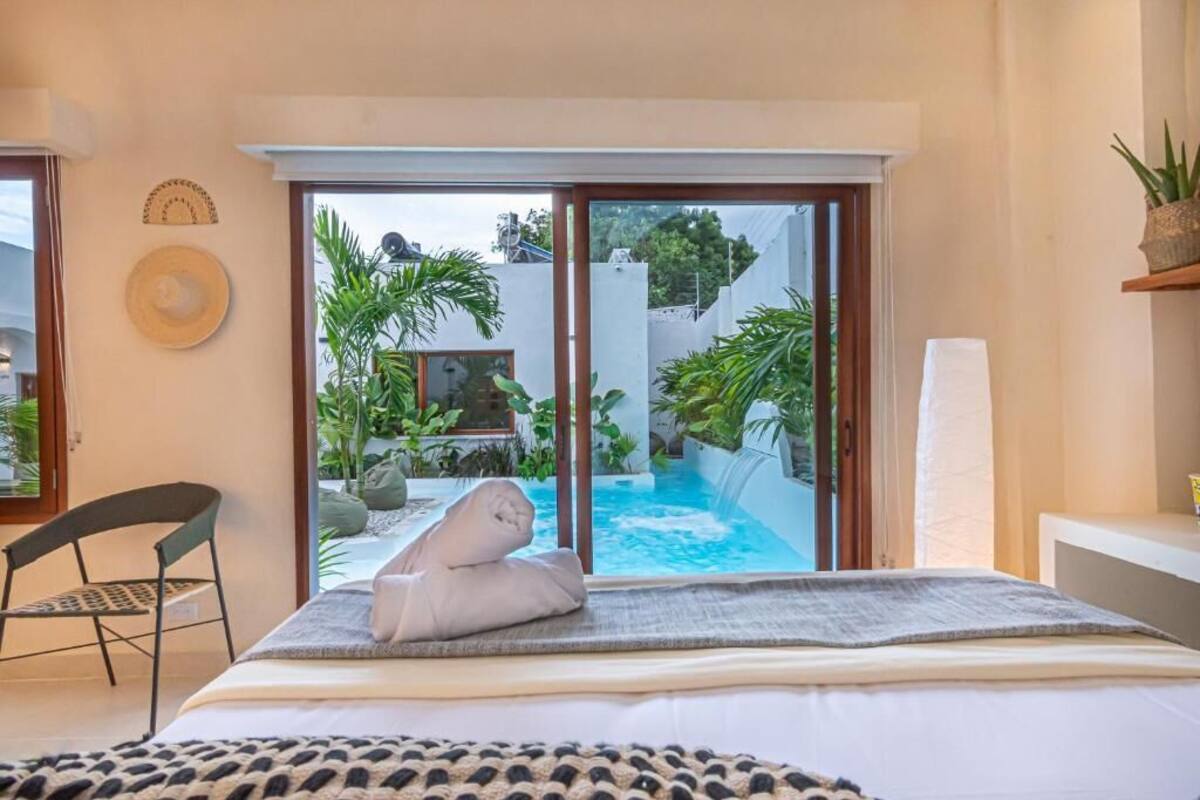 Ein Schlafzimmer mit Bett, Stuhl, Handtuch und Blick auf Pool und Garten.