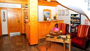 Interior de madeira com balcão de recepção, sofá, estante e uma porta com a inscrição 'Dresch'.
