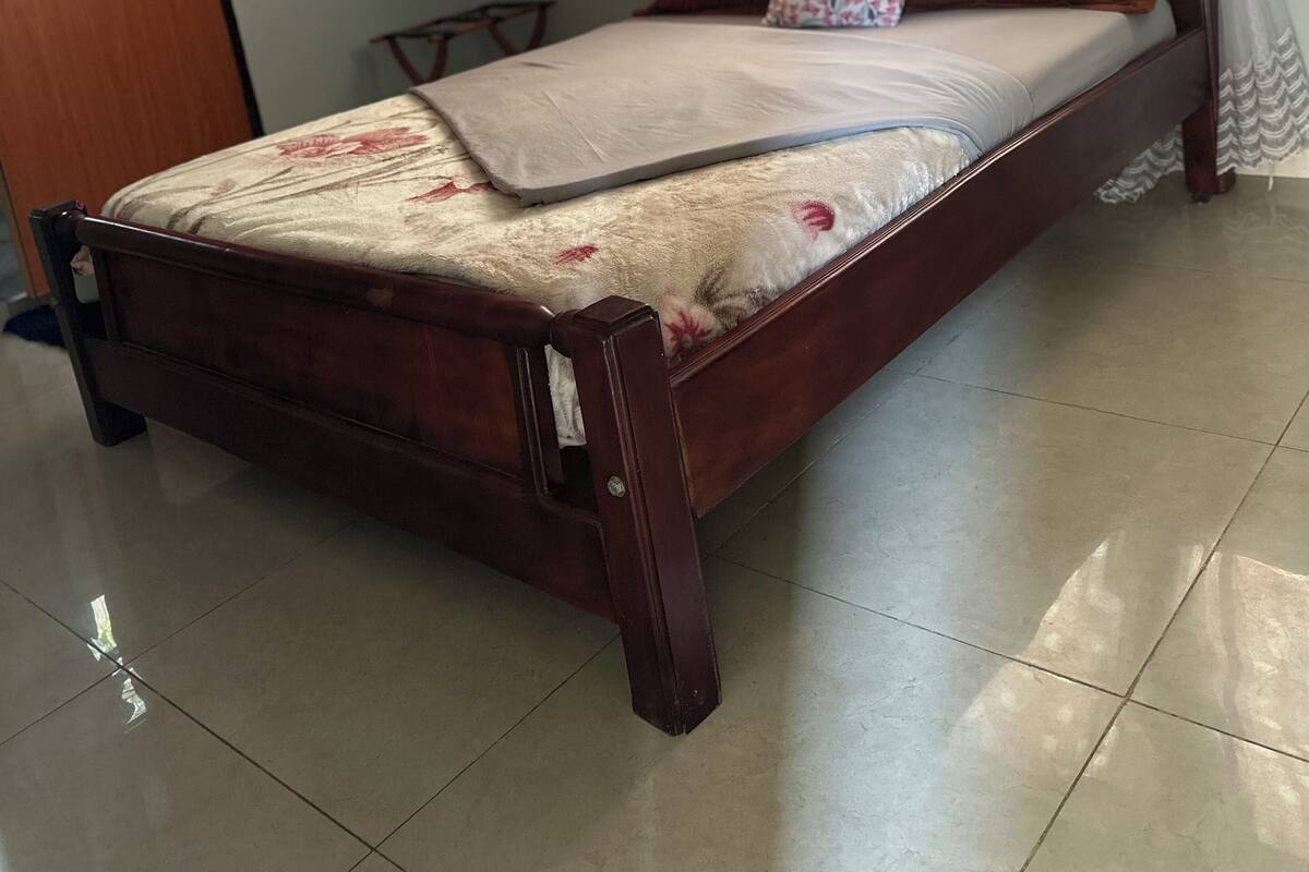 A wooden bed with a floral bedspread and a laptop on it.