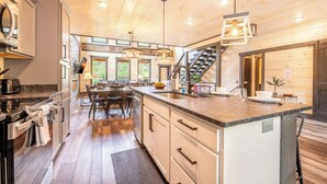 Una cocina moderna con una isla central, electrodomésticos integrados y una escalera que sube a otro nivel.