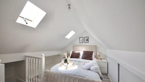 A bedroom with a bed, bedside table, lamp, and a small window. - Modern City Apartment in London (London)