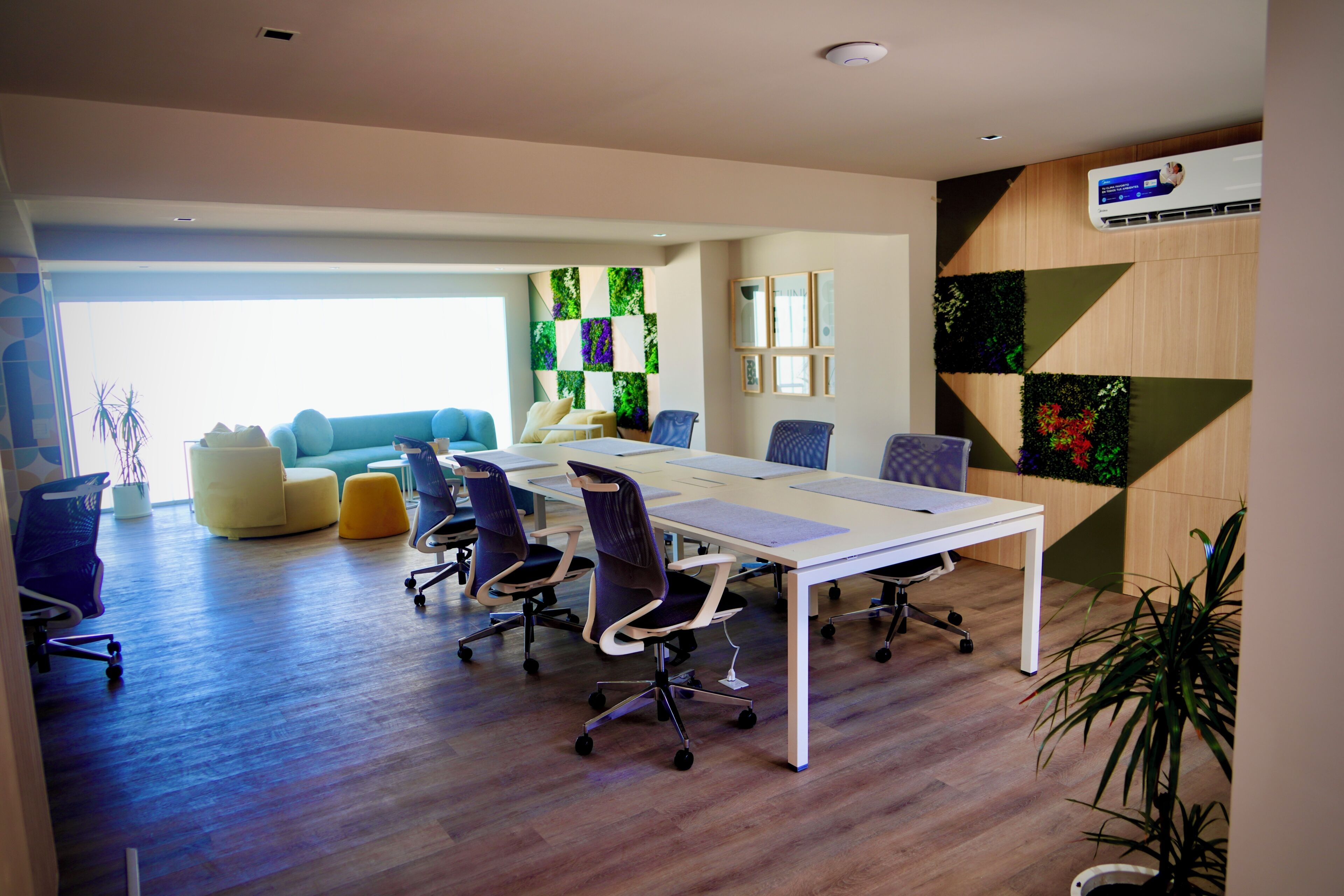 A conference room with a long table, several chairs, a sofa, and a decorative wall with geometric patterns.