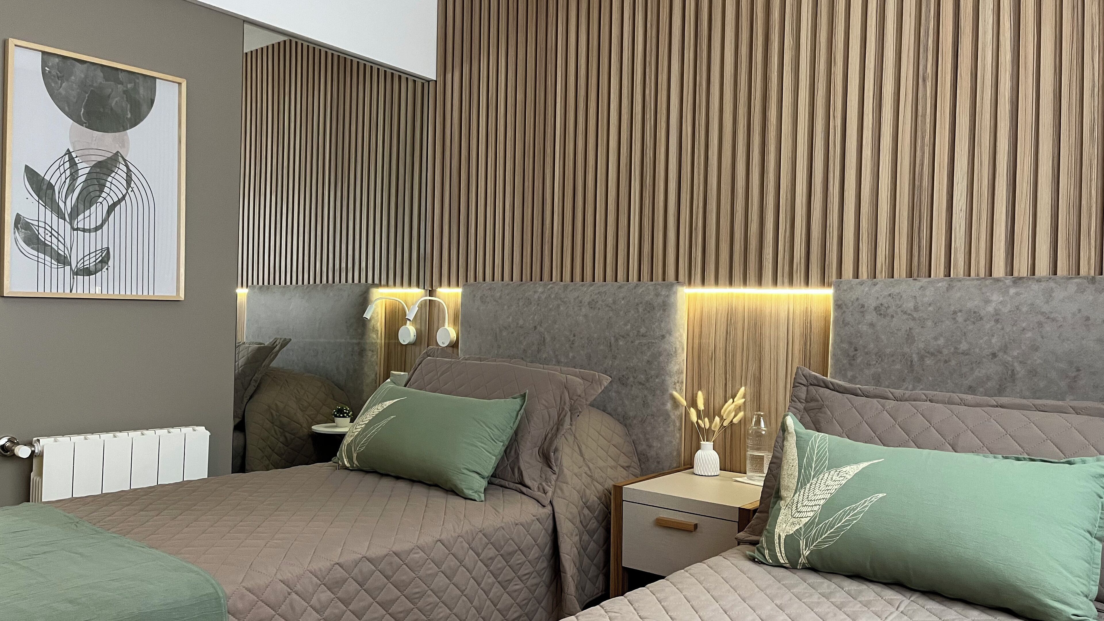 A modern bedroom with a large bed, bedside tables, and a wall-mounted light fixture.