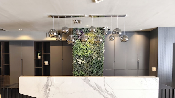 A reception desk with a marble top, a green vertical garden, and a ceiling with hanging spherical lights. - Empire Hotel Buenos Aires (Buenos Aires)