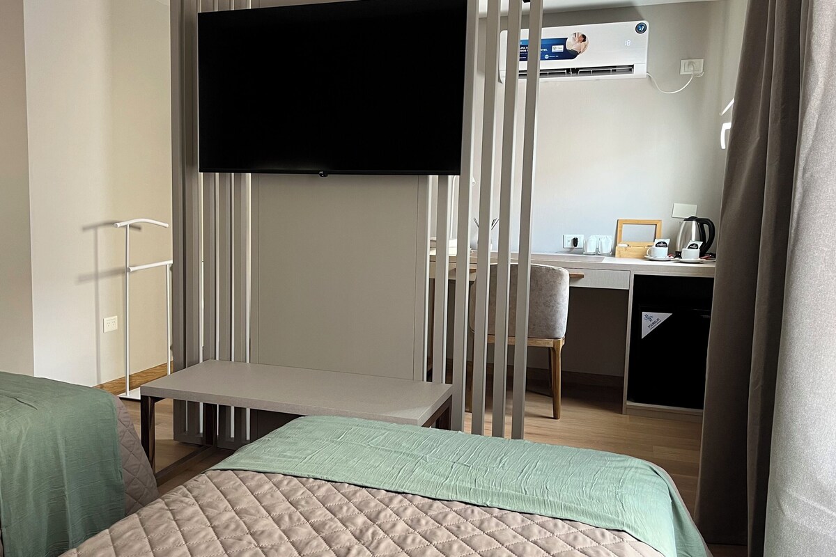 Ein Hotelzimmer mit zwei Betten, einem Fernseher, einem Schreibtisch und einem Stuhl.