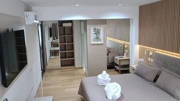 Une chambre d’hôtel comprenant un lit, des tables de chevet, un téléviseur, une armoire et une salle de bain.