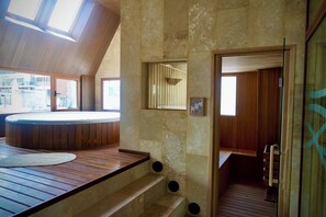 A spa area with a hot tub, wooden flooring, and a stone wall. - Empire Hotel Buenos Aires (Buenos Aires)