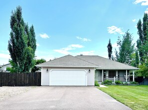 A single-story house with a white garage door, a covered porch, and a fenced yard.