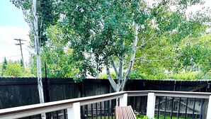 A wooden deck with two lounge chairs and a round table. - Stay between Glacier and Whitefish-cozy stylish (Columbia Falls)