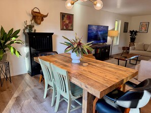 Un comedor con una mesa de madera, sillas y una planta en maceta.