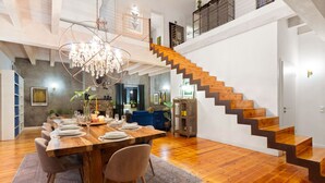 A spacious dining area with a wooden table set for six, a chandelier, and a staircase leading to an upper level. - Higgo Crescent Villa (Cape Town)
