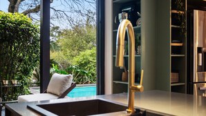 A modern kitchen with a stainless steel sink and a view of a swimming pool. - Higgo Crescent Villa (Cape Town)