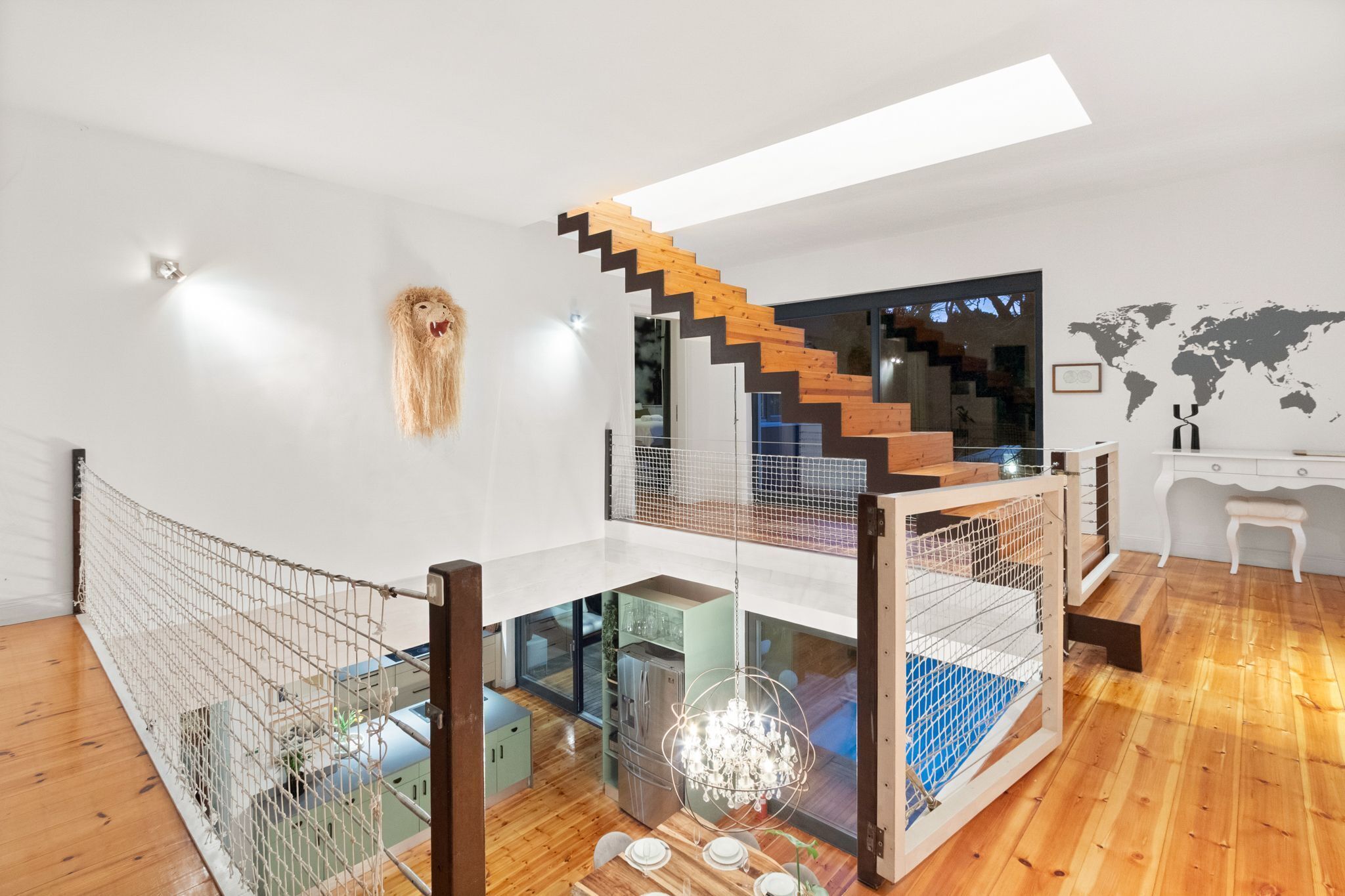 Ein modernes Interieur mit einer Holztreppe, einer Glastrennwand und einer Kronleuchter.