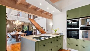 A modern kitchen with green cabinets, a wooden island, and built-in ovens. - Higgo Crescent Villa (Cape Town)