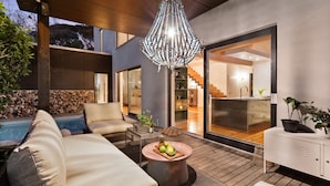 A modern outdoor living area with a pool, lounge chairs, a dining table with fruit, and a large chandelier. - Higgo Crescent Villa (Cape Town)