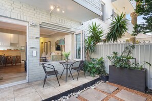 A patio with a table and chairs, a brick wall, and potted plants. - Mimosa Court (Cape Town)