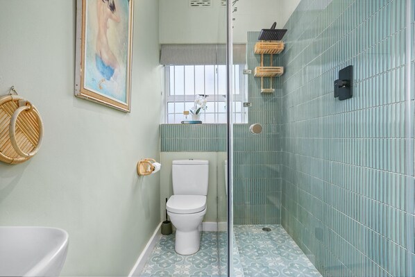A bathroom with a toilet, a shower enclosure, and a wall-mounted sink.