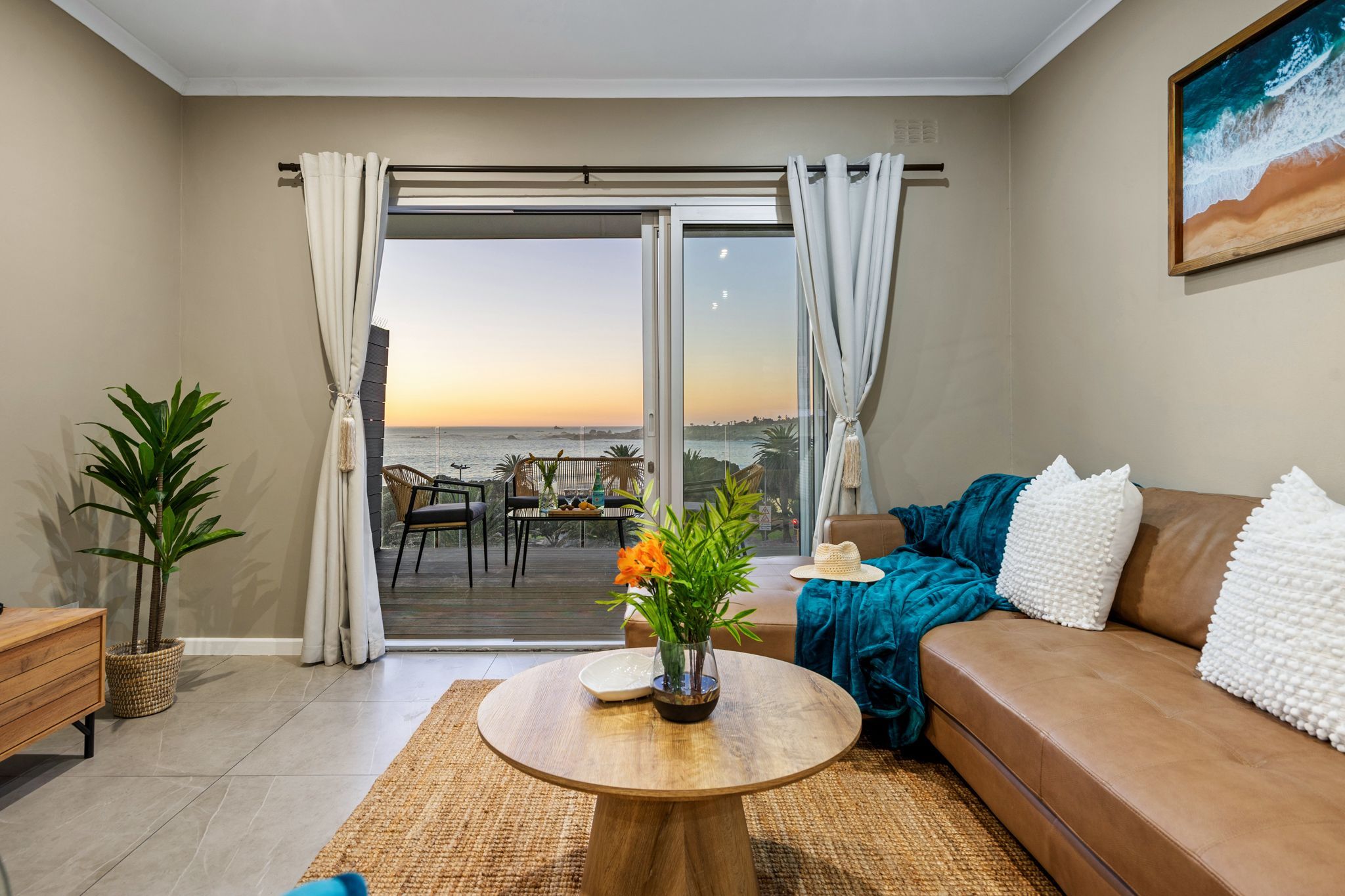 A living room with a sofa, a coffee table, and a view of the sea through a sliding door.