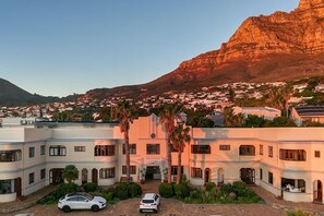 A hotel with a central entrance, surrounded by palm trees and a mountainous backdrop. - Brighton Court (Cape Town)