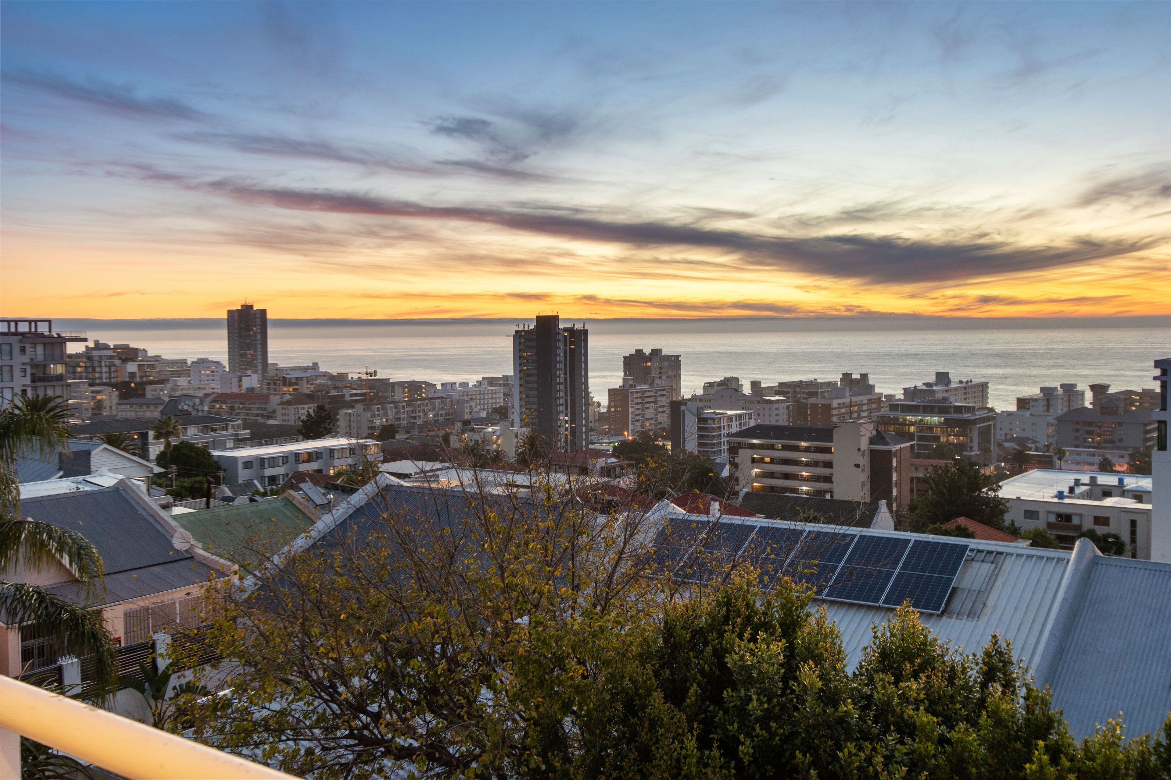 A cityscape with buildings, a clear sky, and a sunset over the water.