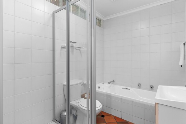 A bathroom with a glass-enclosed shower, a white bathtub, and a sink. - Firdale Mews 5 (Cape Town)