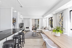 A modern living space with a kitchen area, a dining table, and a seating area with a sofa and chairs. - Sausalito 201 (Cape Town)