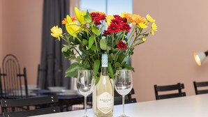 A table with a floral arrangement and two wine glasses, a bottle of wine, and a vase. - Summerville 20 (Cape Town)