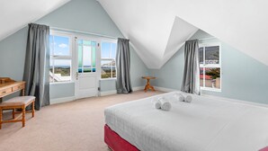 A bedroom with a bed, a desk, and two windows with curtains. - Summerville 20 (Cape Town)