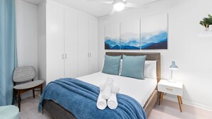 A modern bedroom with a bed, a ceiling fan, a nightstand, and a wall-mounted plant. - Green Market Place (Cape Town)