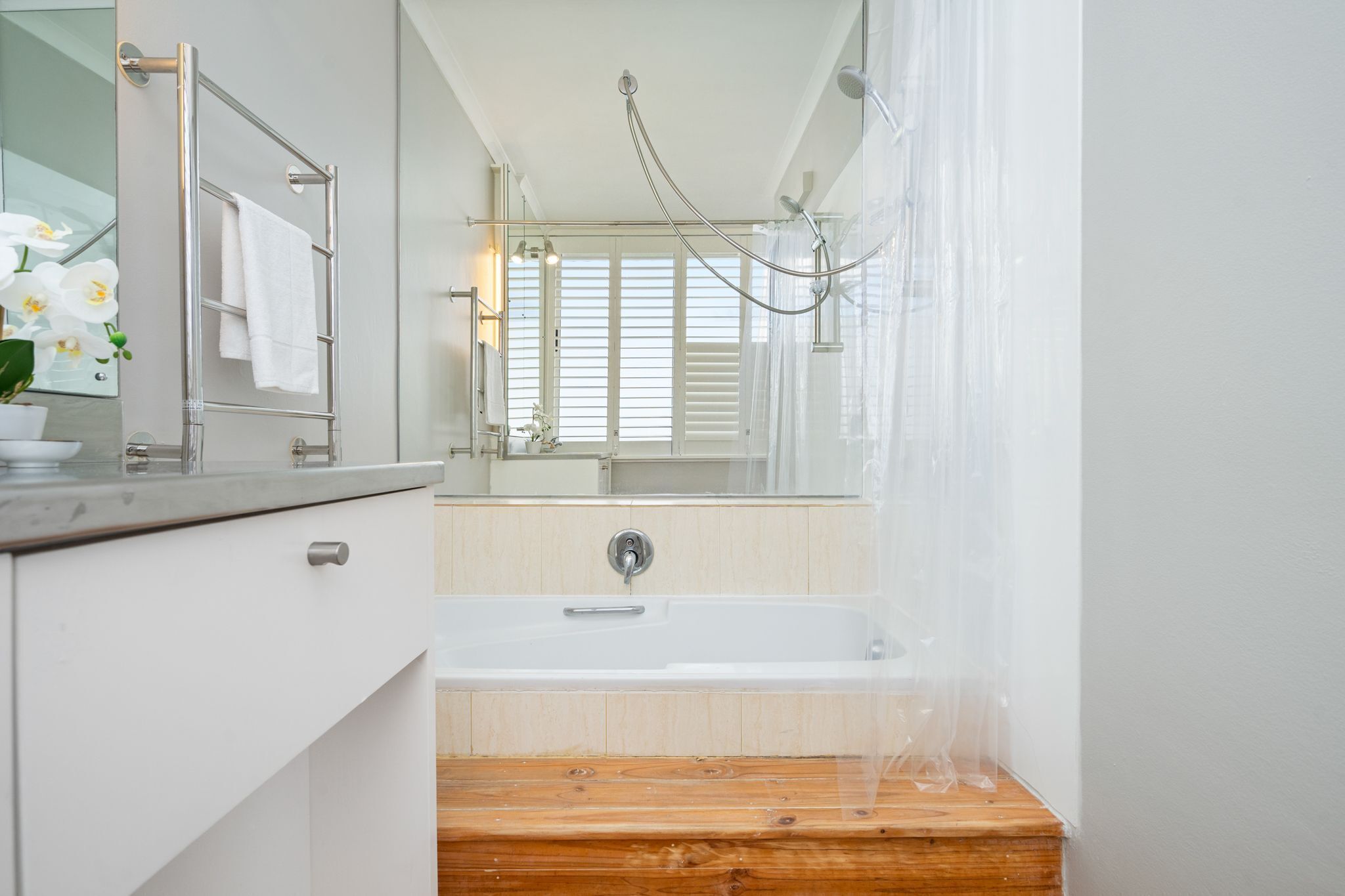 A modern bathroom with a wooden vanity, a large mirror, a bathtub, and a shower with a glass door.