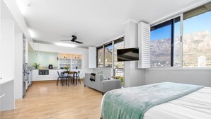 Ένα σύγχρονο δωμάτιο ξενοδοχείου με μεγάλο κρεβάτι, χώρο τραπεζαρίας και κουζίνα.