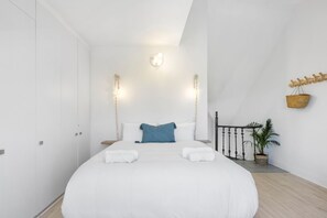 A modern bedroom with a large bed, white walls, and a ceiling light fixture. - Summerville Beach Loft (Cape Town)