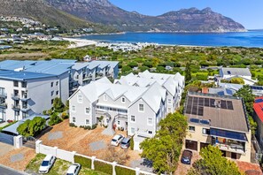 A residential area with modern houses, a large building with a staircase, and a beach in the background. - Summerville Beach Loft (Cape Town)