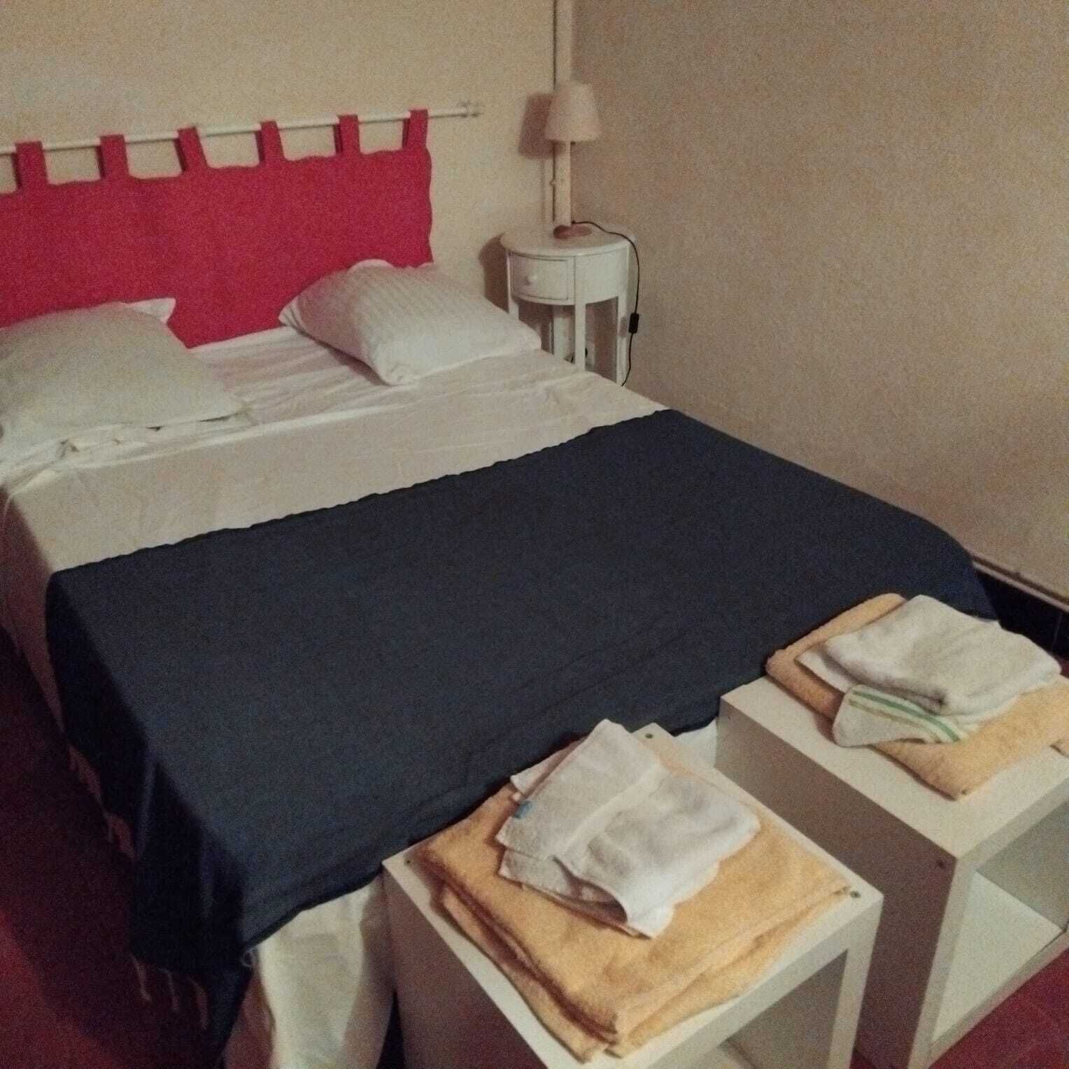 A hotel room with a bed, a nightstand, and a lamp.