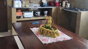 Una cocina con una mesa de madera, dispensador de agua, lavabo, armarios y estufa.