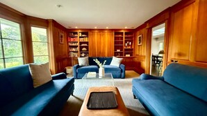 Una sala de estar acogedora con sofás azules, una mesita de centro y estanterías de madera llenas de libros.