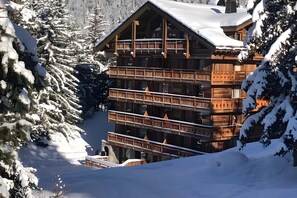 Eine mehrstöckige Holzhütte mit Balkonen, umgeben von schneebedeckten Bäumen.