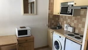 Eine kleine Küche mit Mikrowelle, Spüle, Herd und Waschmaschine.