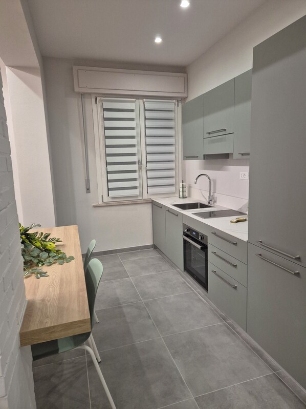 A compact kitchen with a window, a sink, and a dining area with a table and chairs.
