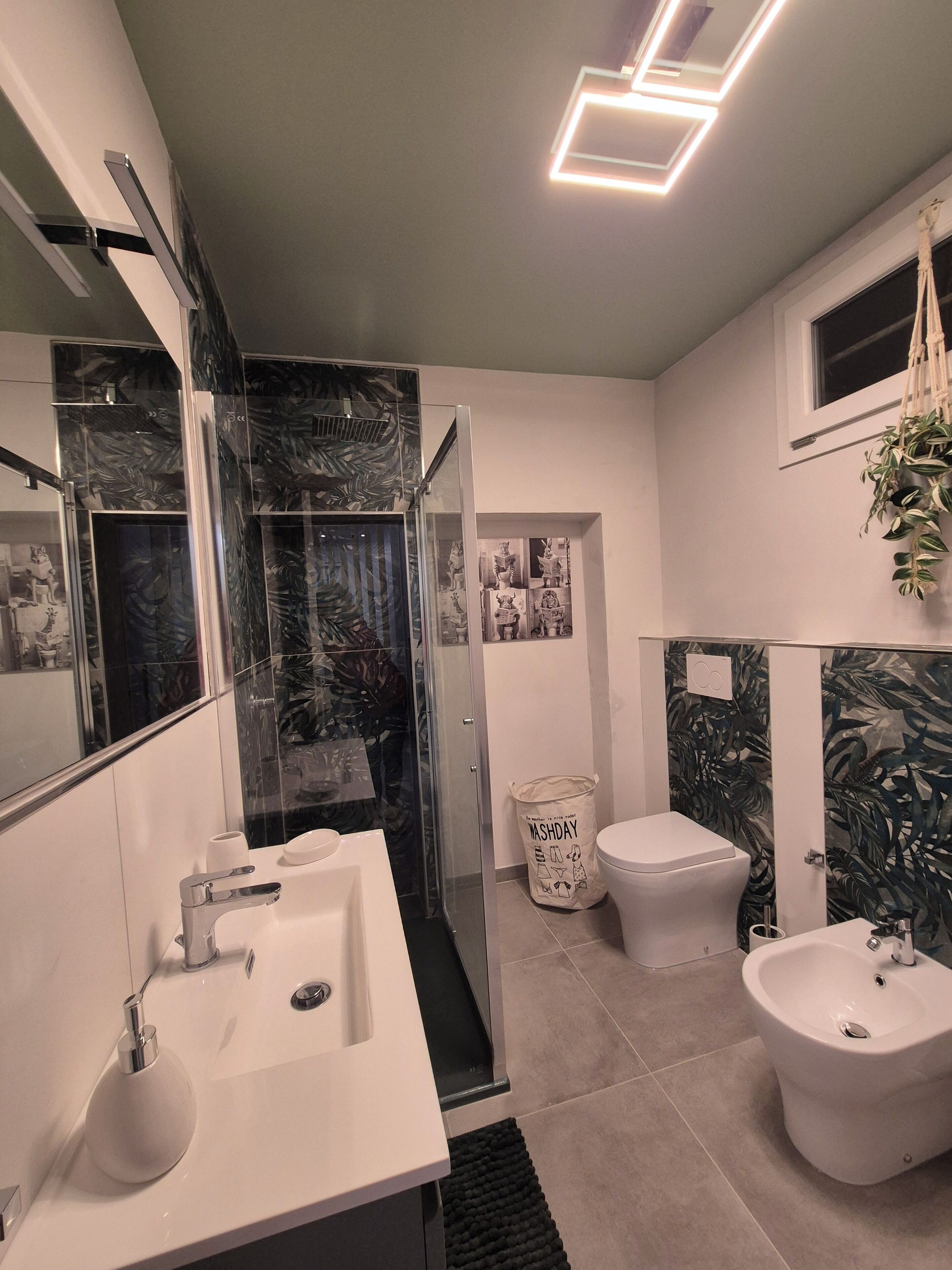 Une salle de bain moderne avec une douche en verre, un bidet et un grand miroir.