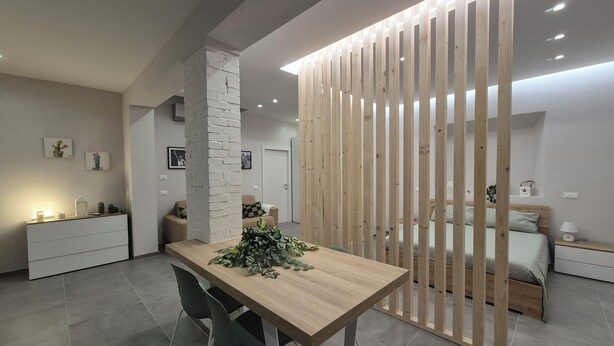 A modern kitchen with a wooden dining table, two chairs, and a decorative plant. - Love Pisa | Elegante Loft nel cuore di Pisa (Pisa)