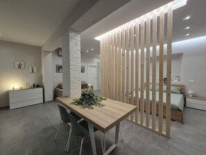 A modern kitchen with a wooden dining table, two chairs, and a decorative plant.