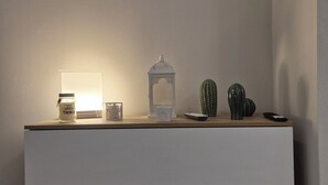 A minimalist room with a white dresser, a wall-mounted light, and two framed cactus paintings. - Love Pisa | Elegante Loft nel cuore di Pisa (Pisa)
