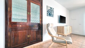A room with a wooden cabinet, a cushioned chair, a television, and a zebra artwork on the wall. - El Charcón A • 10 meters to the beach • LVH (Arrieta)