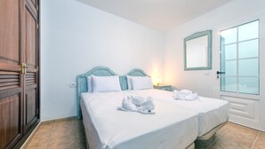 A hotel room with two beds, a wooden wardrobe, a mirror, and a window with frosted glass. - El Charcón A • 10 meters to the beach • LVH (Arrieta)