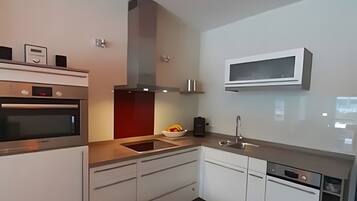 A modern kitchen with built-in appliances, a microwave, and a sink.