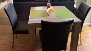 Una sala de estar moderna con una mesa de comedor, sillas de cuero negro, un sofá y una televisión.