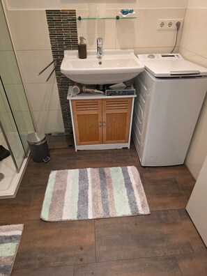 Une salle de bain équipée d’un lavabo, d’un miroir, d’un porte-serviettes et d’un lave-linge.