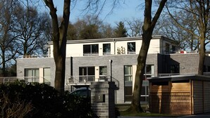 Un edificio moderno con fachada de ladrillo, ventanas amplias y una entrada protegida por una reja.